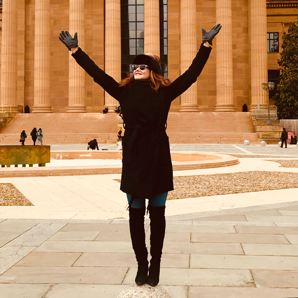 photo of robyn posing with her arms towards the sky smiling